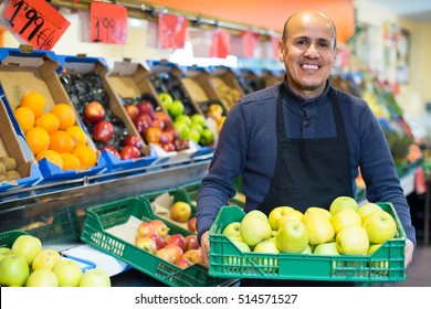 Portrait of friendly smiling mature man selling seasonal fruits at market - Powered by Shutterstock