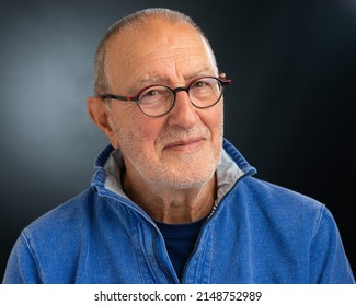 Portrait Of A Friendly Smiling Older Man Wearing Glasses On A Dark Background