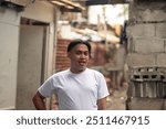 Portrait of a friendly young man standing in front of a slum area. A young Filipino residing in an squatter area. Shantytown background.