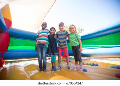 Portrait of friends with arms around standing on bouncy castle at playground - Shutterstock ID 670584247