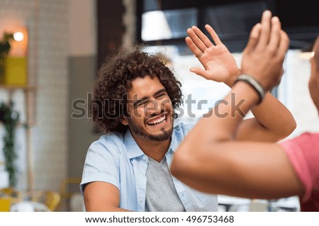 Portrait of friends giving high five at cafe while having lunch. Young guys friends giving a high five, slapping each others hand in congratulations while sitting in cafeteria.