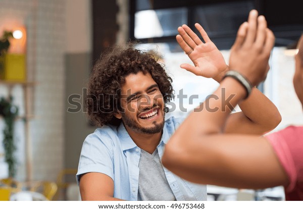 Portrait of\
friends giving high five at cafe while having lunch. Young guys\
friends giving a high five, slapping each others hand in\
congratulations while sitting in\
cafeteria.