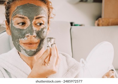 Portrait front view of young woman with skin cream treatment on face inside a camper van. Beauty anti aging mud on female people. Lady using natural skin care product looking on a mirror. Youthful - Powered by Shutterstock