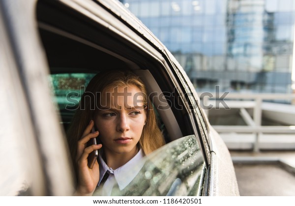 Portrait of frown girl\
in car with mobile