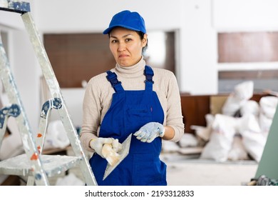 Portrait Of Frustrated Asian Woman Builder With Float Trowel Standing In Apartment.