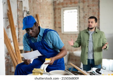 Portrait Of Frustrated Builder Holding Dismissal Letter At Indoors Building Construction Site, Annoyed Foreman Gesturing On Background