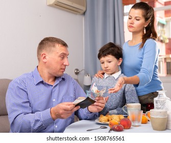 Portrait Of Frustrated Man Giving Money To Strict Wife And Tween Boy In Home Interior