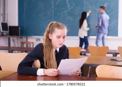 Portrait Of Frustrated Teen Girl Student Sitting In Classroom With Paper, Reading Notification About Failed Test 