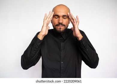 Portrait Of Frustrated Young Man Rubbing Temples. Upset Multiethnic Male Model With Bald Head And Beard In Black Shirt With Closed Eyes Massaging Head. Headache, Tiresome Concept