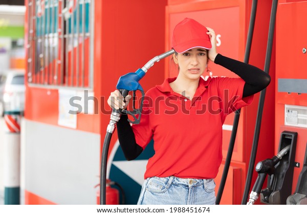 portrait frustrated
young woman worker holding petrol hose and her face a trouble
something at the gas
station
