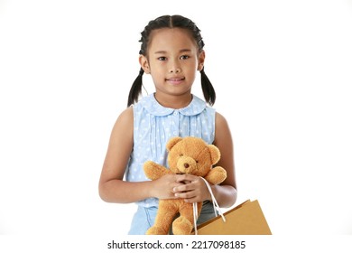 Portrait Full Body Studio Cutout Shot Asian Young Pigtail Braid Hair Shopper Girl In Blue Dress Standing Smiling Holding Brown Bear Doll And Paper Shopping Bag Look At Camera On White Background