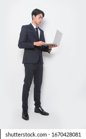 Portrait Of Full Body Young Man In White Shirts ,black Suit, Tie Standing Holding Laptop On White Background 


