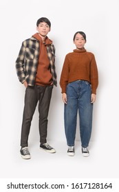 Portrait of Full length fashion young couple man and woman
 in brown sweater and jacket and jeans, sneakers, posing in studio

 - Shutterstock ID 1617128164