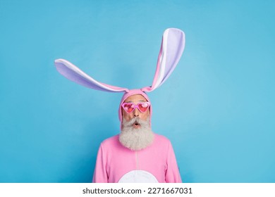 Portrait of funky astonished positive elderly pensioner wear pink bunny costume impressed staring isolated on blue color background