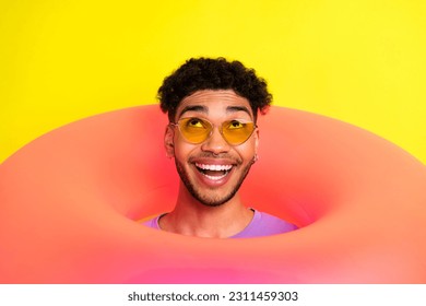 Portrait of funky positive handsome man head through inflatable ring hole look up empty space isolated on yellow color background - Shutterstock ID 2311459303
