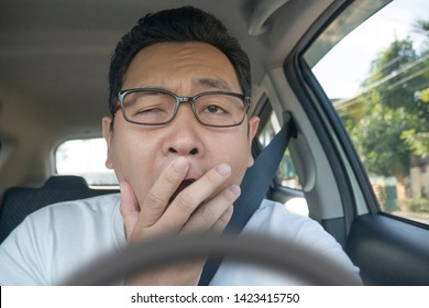 Portrait of funny Asian male driver get bored in his car trapped in traffic jam, tired lazy facial expression gesture