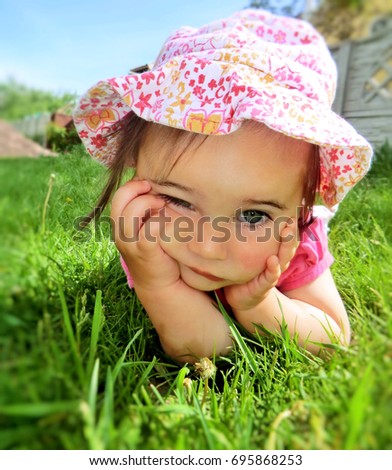 Similar – Littel girl sitting on grass looking curious