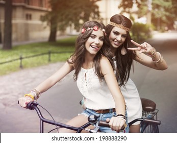 Portrait Of Funny Boho Girls On The Tandem Bicycle