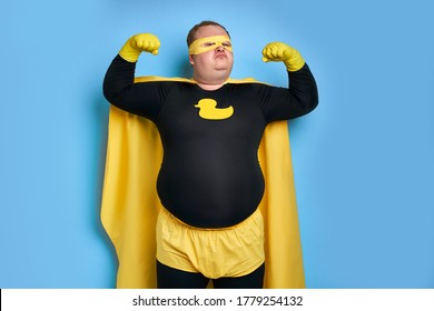 portrait of funny caucasian superhero with arrogant face isolated over blue background. man shows his strength and competence at camera