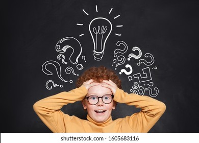 Portrait Of Funny Child Boy With Lightbulb On Blackboard