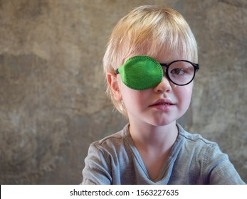 Portrait of funny child in new glasses with patch for correcting squint. Ortopad Boys Eye Patches nozzle for glasses for treatment of strabismus (lazy eye)