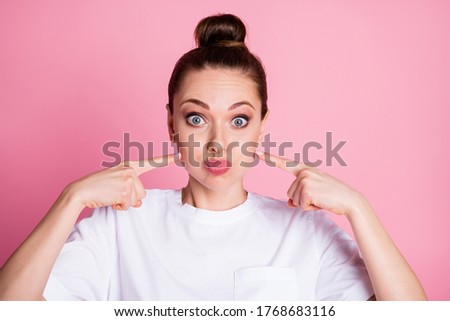 Portrait of funny childish girl inflating cheeks point index finger wear good look clothes isolated over pink color background