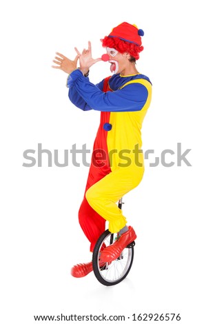Portrait Of A Funny Clown Performing On Unicycle Over White Background
