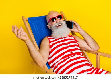 Portrait of funny cool pensioner man lying on sunbed at summer resort and phone calls abroad isolated over yellow color background - Powered by Shutterstock