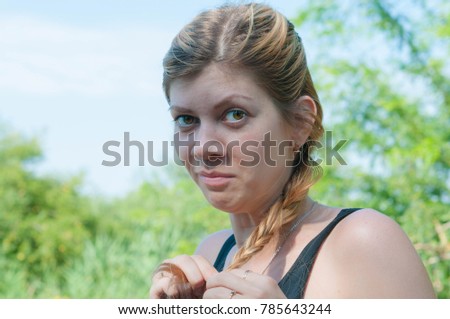 Portrait of Funny cute blond girl in warm sunny day weaves a braid