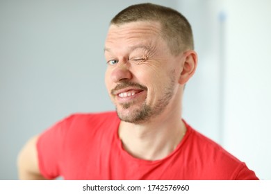 Portrait Of Funny Cute Man Posing On Camera. Joyful Person Making Faces. Mature Middle-aged Male In Red Tshirt. Adult Winking Standing Indoors. Modern Concept