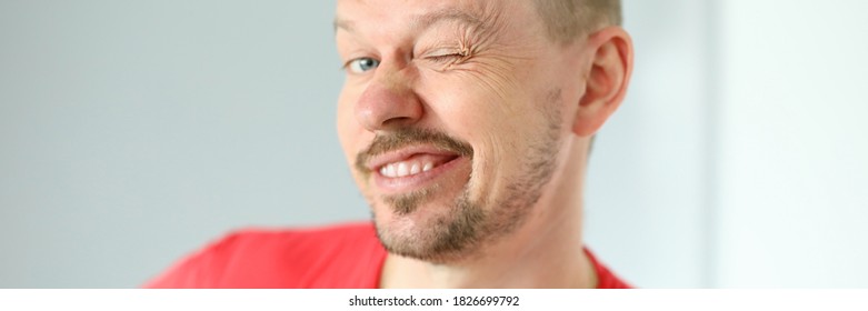 Portrait Of Funny Cute Man Posing On Camera. Joyful Person Making Faces. Mature Middle-aged Male In Red Tshirt. Adult Winking Standing Indoors. Modern Concept