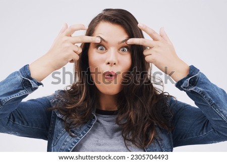 Portrait, funny face and eyes with a woman in studio on a gray background looking silly or goofy. Comedy, comic and crazy with a playful young female person joking indoor for fun or carefree humor