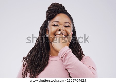 Portrait, funny face and finger on nose with a black woman in studio on a gray background looking silly or goofy. Comedy, comic and nostril with a crazy young female person joking for fun or humor