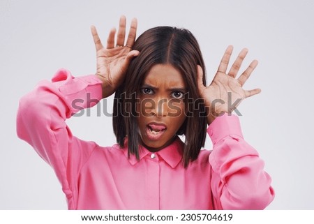 Portrait, funny face and hands with an indian woman in studio on a gray background looking silly or goofy. Comedy, comic and gesture with a crazy young female person joking indoor for fun or humor