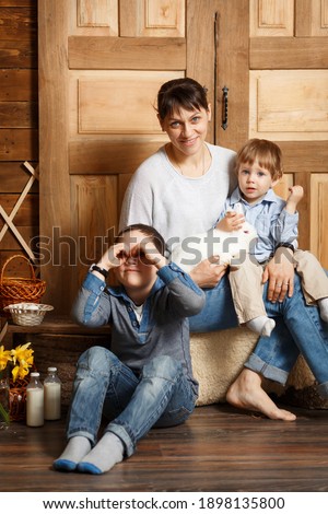 Portrait of funny family playing egg hunt outdoor at wooden country house. Kids on rural background with easter bunny. Concept of Easter or Mother Day celebration. Country style.