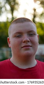 Portrait Of Funny Fat Teenager In Red Shirt With Buzz Cut. Boy Grinned With Open Mouth