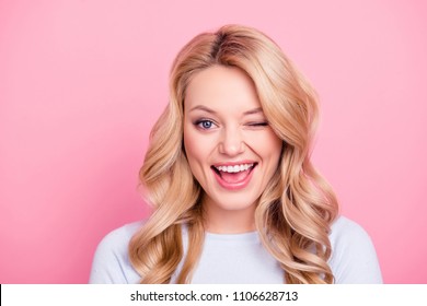 Portrait of funny foolish girl with modern hairdo winking with one eye open mouth, playing with lover isolated on pink background