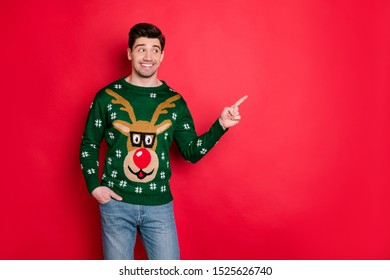 Portrait Of Funny Funky Brown Hair Man In Deer Reindeer Theme Sweater Point Index Finger At Copy Space Recommend Ads Winter Shopping Sales  Isolated Over Red Color Background