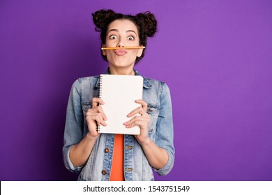 Portrait of funny funky girl do essay want rest relax make break pause fool grimace pencil between nose lips pouted plump hold note book wear trendy jeans clothes isolated violet color background