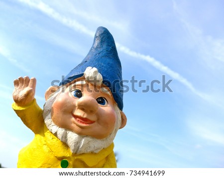 Portrait of a funny garden dwarf against a blue sky with little clouds
