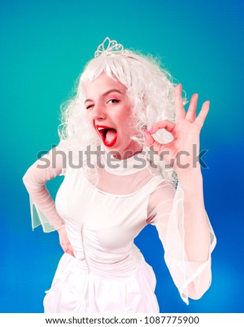 Portrait of funny girl in blonde wig show OK. Studio shot.