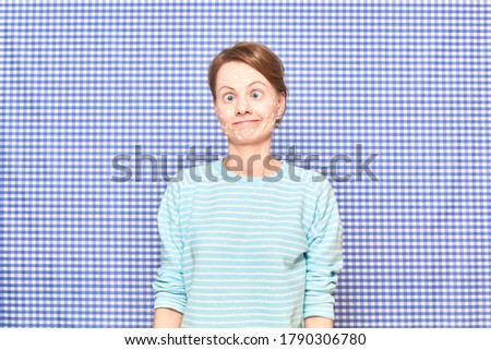 Portrait of funny goofy girl with anti-acne skincare product on face, with crossed eyes, looking perplexed, bewildered and amazed, over shower curtain background. Care for problem skin. Beauty concept