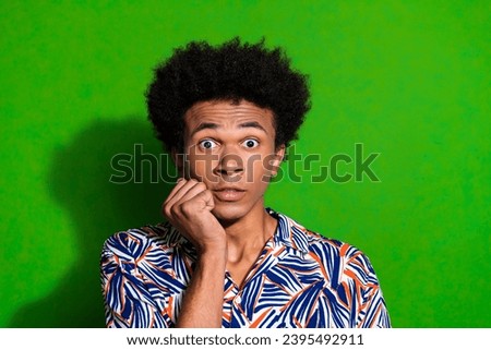 Portrait of funny guy frightened when watching scary thriller movie in cinema touch cheek stressed isolated on green color background