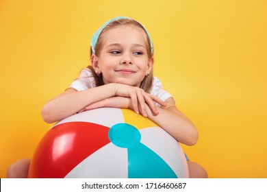 Portrait Of Funny Happy Child In Summer Clothes With Beachball On Yellow Background