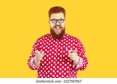 Portrait of funny happy joyful charismatic fat bearded man in polka dot shirt and eyeglasses smiling and pointing his index fingers at camera as if saying Let's have fun or Exactly, I agree with you