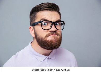 Portrait of a funny hipster man looking at camera over gray background