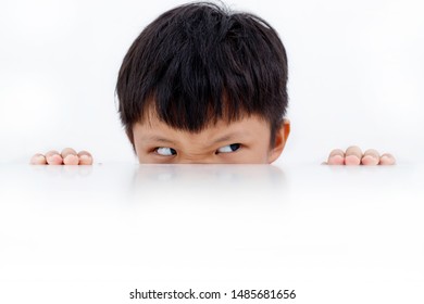 Portrait Of Funny Little Boy Looking Left From Under The Table Isolated On White Background.