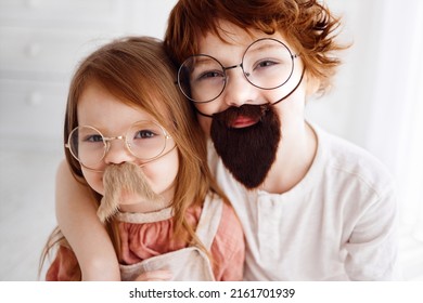 portrait of funny little siblings having fun, wearing false mustache