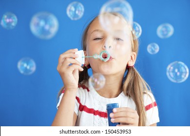 Portrait of funny lovely little girl blowing soap bubbles