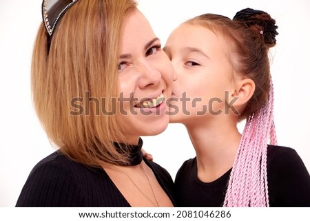 Portrait of Funny Mother and daughter in same outfits posing on studio on the white background